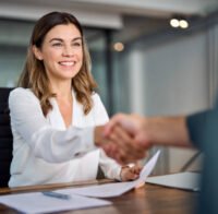 Happy mid aged business woman manager handshaking at office meeting. Smiling female hr hiring recruit at job interview, bank or insurance agent, lawyer making contract deal with client at work.